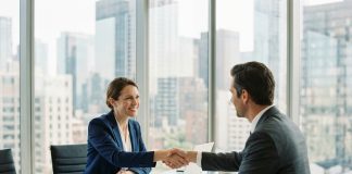 Femme d'affaires en costume navy serre la main d'un client dans un bureau moderne